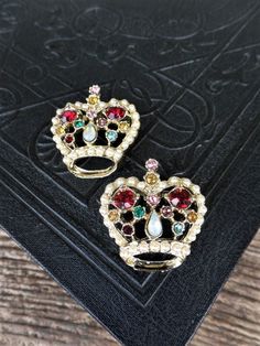 This listing is for the set of two vintage crown pins. These are beautiful, and covered in rhinestones and pearls. There are ruby red stones, opals, green, amber, pink, and pearls. The metal is gold tone. Each pin is 1 1/2 in. long, and 1 1/4 in. wide. Both are in great vintage condition. Thank you Regency Costume, Crown Brooch, Patriotic Jewelry, Holiday Necklace, Vintage Crown, Vintage Lockets, Mid Century Jewelry, Mid Century Mod, Gold Charm Bracelet