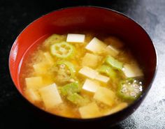 a red bowl filled with soup sitting on top of a table next to a black counter