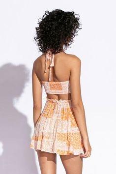 STYLE INFORMATION: Get your Texas boho vibes on in the Sundown Orange Patchwork Print Sundress!. Orange patchwork print woven fabric shapes this cute dress that has a halter V-neckline with tie straps, and a cutout waist.. The open back wraps around to the sides to create a cutout effect above the attached mini skirt. Ruffle trim and side ties decorate the cutout waist. DETAILS & CARE: Rayon/Polyester. Dry Clean. Imported. SHIPPING: Orders are processed within 1-2 business days. Packages are shi Bohemian V-neck Halter Top For Summer, Summer V-neck Tie Back Halter Top, Halter Neck Tie Back Sundress For Beach Season, Summer Backless Halter Top With Smocked Back, Cutout Halter Top For Beach In Summer, Beach Halter Neck Sundress With Tie Straps, Backless Smocked Back Halter Top For Summer, Spring V-neck Halter Top With Tie Back, Beach Halter Top With Spaghetti Straps And Tie Back