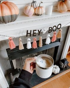 a person holding a cup in front of a fire place with decorations on the mantle