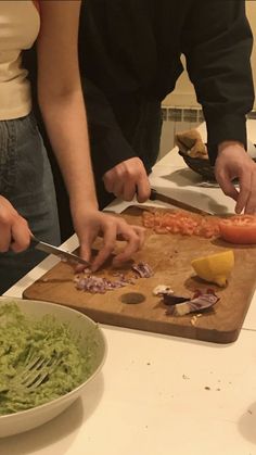 two people are preparing food on a cutting board