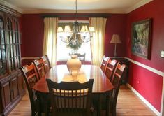 a dinning room table with chairs and a vase on top of it in front of a window