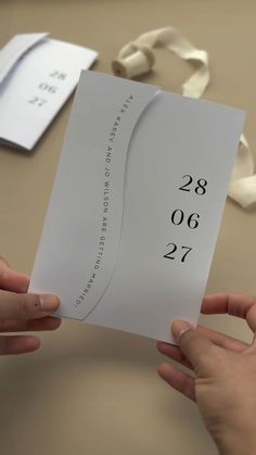 two hands holding a piece of paper with numbers on it