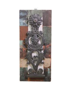 a metal plaque with a face and flower on it's side, against a multicolored background