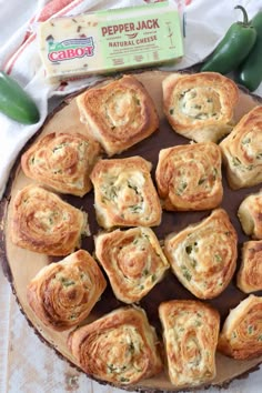 some food is laying on a wooden platter with green peppers and cheeses in it