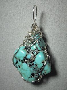 Turquoise Nugget Pendant Wire Wrapped in .925 Sterling Silver Round Wire This inspiring stone offers a few small pebbles of golden pyrite nestled inside a light to medium turquoise-blue and black patterned background. Best worn with blue, green, coral, orange, or red; but quite versatile, and many dark, bright, pastel, and earth tone colors also wear well, especially black, grays, brown, beige/tan, and lavender. A similar color of turquoise will blend, so should be avoided. Some darker purple co Silver Turquoise Gemstone Necklace For Healing, Sterling Silver Turquoise Necklace With Stones, Spiritual Turquoise Jewelry With Large Stone, Sterling Silver Turquoise Ring With Stones, Unique Turquoise Nickel-free Necklace, Blue Turquoise Necklace With Stones, Unique Nickel-free Turquoise Necklace, Unique Blue Turquoise Necklace With Stones, Turquoise Stone Ring As A Gift