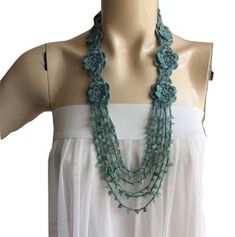 a mannequin wearing a white dress and green necklace