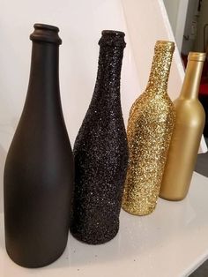 three black and gold vases sitting on top of a white shelf next to each other