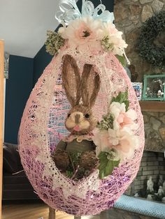 an easter egg decorated with flowers and a bunny in the center is sitting on a stand