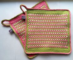 two pink and green crocheted placemats sitting on top of each other