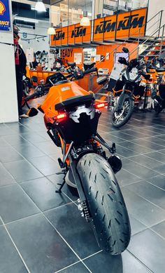 an orange motorcycle is parked in a showroom