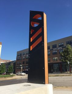 a large black and orange sign sitting on the side of a road in front of a building