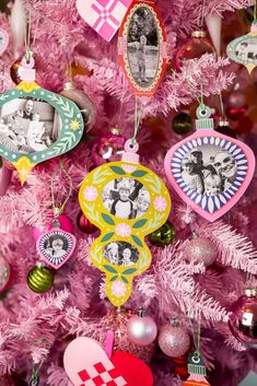 a pink christmas tree with ornaments and pictures hanging from it's branches in the shape of hearts