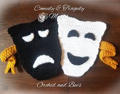 two crocheted masks with faces on them sitting on top of a wooden table