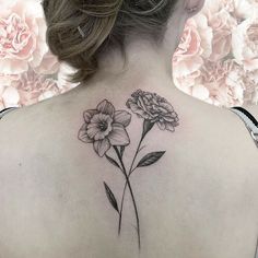 the back of a woman's shoulder with two flowers on her left and one flower on her right side