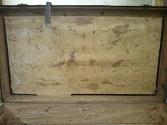 an old wooden box sitting on top of a floor next to a wall and window