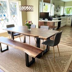 a dining room table with two benches in front of it and an area rug on the floor