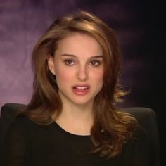 a woman in black shirt sitting down with her hand on her hip and looking at the camera