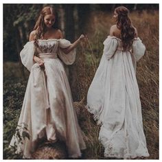 two women in white dresses walking through the woods