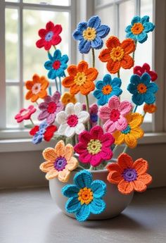 crocheted flowers in a white vase on a window sill