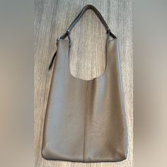 a large gray purse sitting on top of a wooden table next to a white wall