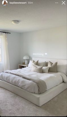 a white bed sitting in the middle of a bedroom next to a window with curtains