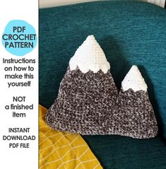 a crocheted mountain pillow sitting on top of a green couch