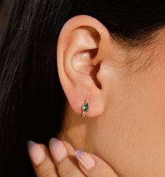 A bold green cubic zirconia adorns this delicate huggies. The chunky frame makes these beauties stand out but they're still subtle enough to wear everyday. Dress up your date night with this sultry pair of earrings or wear them to complement your eyes. Green Huggie Earrings With Matching Set, Green Fine Jewelry Huggie Earrings For Gift, Dainty Green Huggie Jewelry, Green Dainty Huggie Jewelry, Green Tarnish-resistant Huggie Jewelry, Green Huggie Earrings For Everyday Wear, Green Small Hoop Earrings Tarnish Resistant, Small Hoop Green Earrings Tarnish Resistant, Elegant Everyday Hoop Earrings With May Birthstone