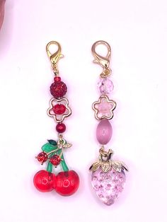 two charms with cherries and berries hanging from them