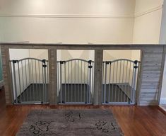 a dog gate in the middle of a room with hardwood floors and walls, along with a rug on the floor