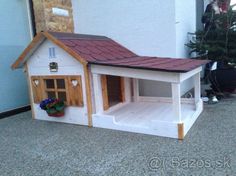 a dog house that is made out of wood and has a red shingled roof