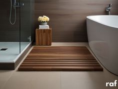 a bathroom with a bathtub, shower and wooden flooring in the middle of it