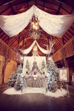 a decorated stage set up for a christmas party with white drapes and snow on the ground