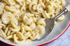 a bowl filled with macaroni and cheese on top of a table next to a spoon