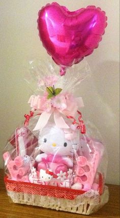 a hello kitty gift set in a basket on a table with a heart shaped balloon