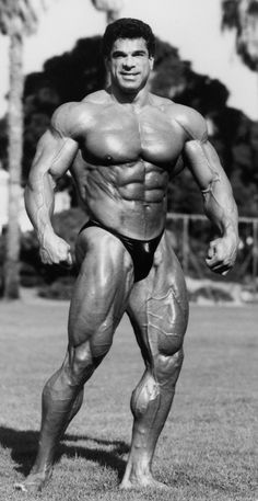 a man with muscles standing in the grass