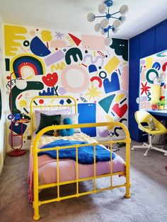 a bedroom with colorful wallpaper and yellow metal bed frame