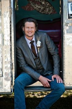 a man in a suit and tie sitting on the back of an old school bus