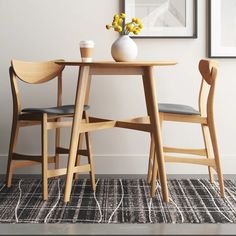 two wooden chairs sitting at a table with a vase on top of it next to each other