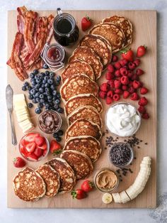 a pancake board with bacon, strawberries and other foods