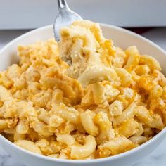 a spoon full of macaroni and cheese in a white bowl