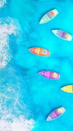 five colorful boats floating in the ocean near each other and one is on the water