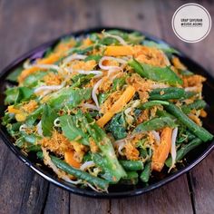 a black plate topped with green beans and carrots