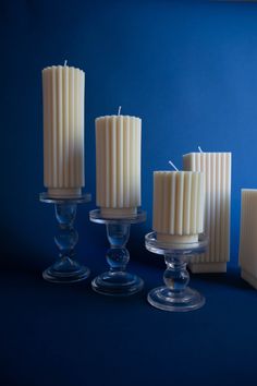 candles are lined up in glass holders against a blue background