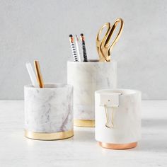 marble pen holder with gold handles and pencils in it on a white countertop