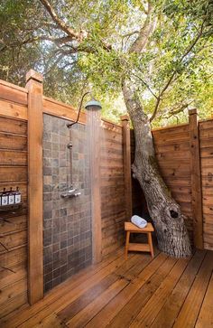 a wooden deck with a tree in the middle and a shower area on one side