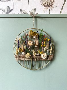 a metal rack with flowers hanging from it's sides on a wall next to a flower pot