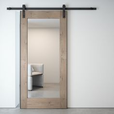 an empty room with white walls and a large wooden door that has a mirror on it