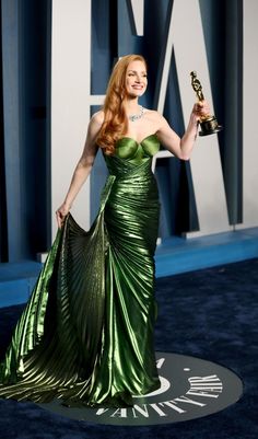 a woman in a green dress holding an award for best actress at the oscars