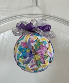 a colorful ornament hanging from a door with purple ribbon and bow on it